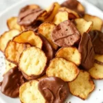 A hand holding a chocolate-covered potato chip, ready to be enjoyed.